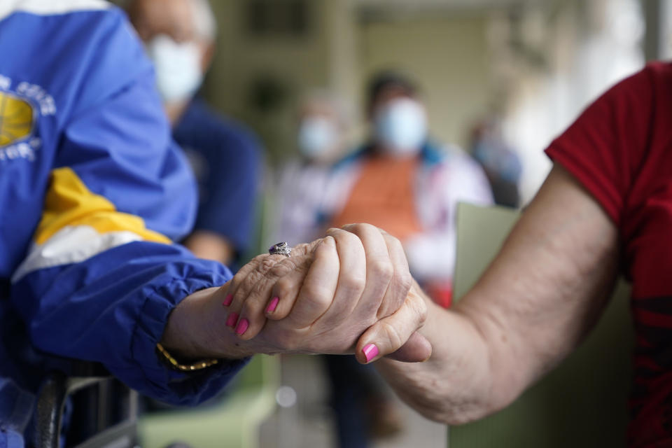 FILE - In this Jan. 12, 2021, file photo residents Ken Fishman, 81, left, and Esther Wallach, 82, right, hold hands as they wait in line for the Pfizer-BioNTech COVID-19 vaccine at the The Palace assisted living facility in Coral Gables, Fla. An ongoing study suggests that older American adults are showing resilience and perseverance despite struggles with loneliness and isolation during the pandemic. (AP Photo/Lynne Sladky, File)