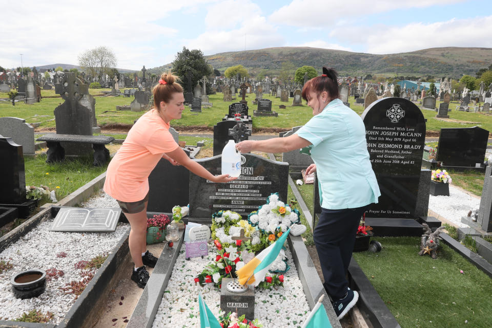 Two women water plants at Milltown Cemetery in Belfast, Northern Ireland, where cemeteries are reopening to the public this weekend, as the UK continues in lockdown to help curb the spread of the coronavirus.