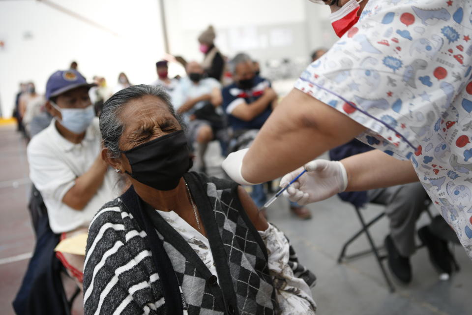 Maria Castrejon, 71, grimaces as she is vaccinated with a second dose of the Sinovac COVID-19 vaccine at the Americas Cultural Center, in Ecatepec, Mexico, Saturday, April 3, 2021. (AP Photo/Ginnette Riquelme)