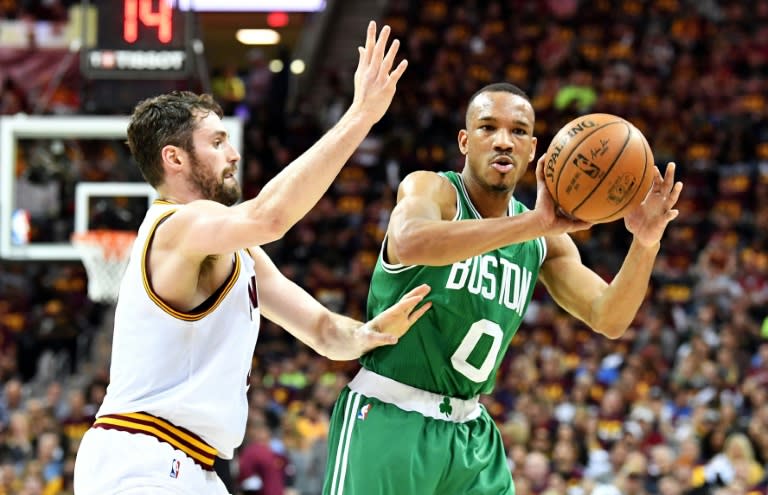 Avery Bradley (R) of the Boston Celtics passes against Kevin Love of the Cleveland Cavaliers in Game Three of the 2017 NBA Eastern Conference Finals, at Quicken Loans Arena in Cleveland, Ohio, on May 21