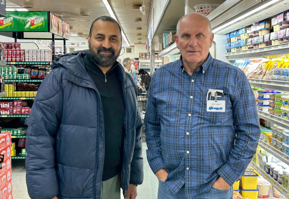 New store owner Sid Ahmed, left, and former owner Jeff Gray, right, pose for a photo on Monday, Nov. 6, in the dairy aisle at Gray's Foods in Rockford, Illinois.