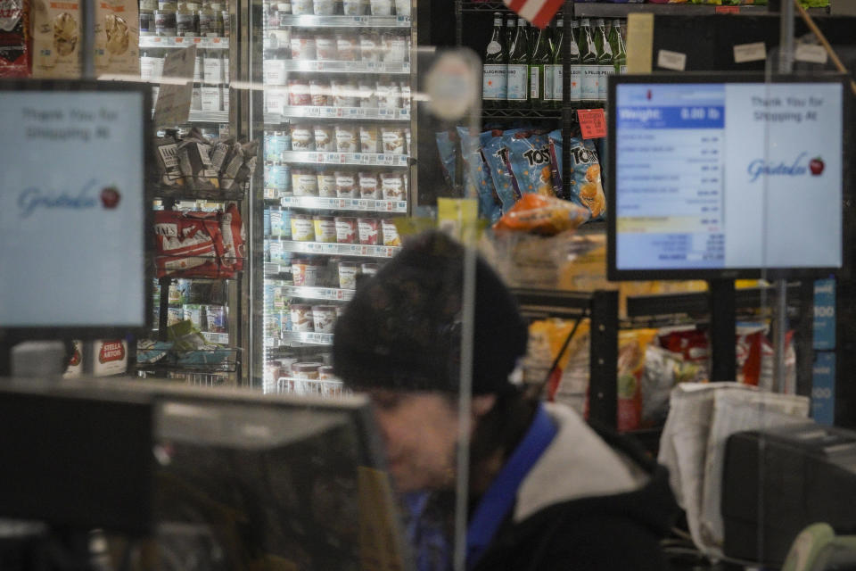 A cashier at a Gristedes supermarket works in view of a freezer holding Haagen-Dazs ice cream, Tuesday Jan. 31, 2023, in New York. "This is a high priority store for theft," said Matthew Calabrese, head of security at the store, who had the ice cream re-positioned within eyesight of cashiers to curtail its theft. (AP Photo/Bebeto Matthews)