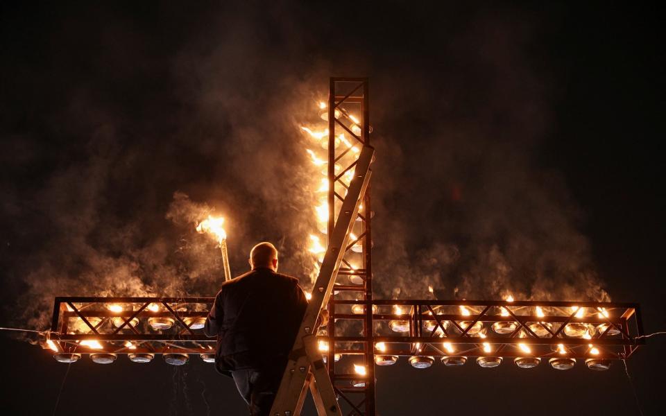 A cross is illuminated in the Colosseum for the Way of the Cross procession