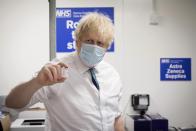 FILE - In this Monday, Jan. 25, 2021 file photo, Britain's Prime Minister Boris Johnson holds a vial of the Oxford AstraZeneca COVID-19 vaccine, during a visit to Barnet FC's ground at the Hive, which is being used as a coronavirus vaccination centre, in London. The European Union’s dispute with AstraZeneca has intensified with the Anglo-Swedish drugmaker denying the EU’s assertion that it had pulled out of talks on vaccine supplies. AstraZeneca said that it still planned to meet with EU officials in Brussels later in the day. The talks will be the third in as many days. AstraZeneca says the figures in its contract with the EU were targets that couldn’t be met because of problems in rapidly expanding production capacity. (Stefan Rousseau/Pool Photo via AP, File)