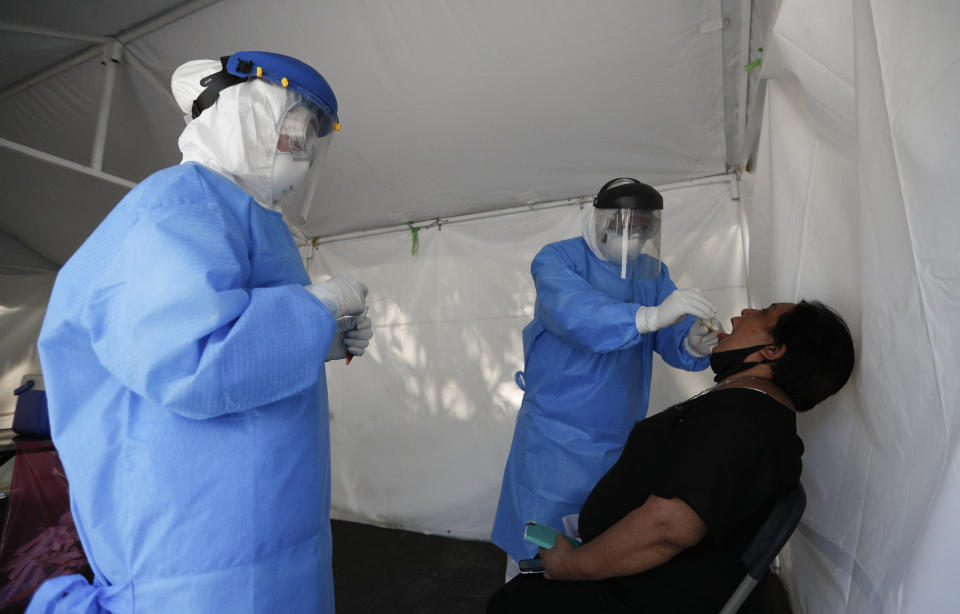 A healthcare worker collects a sample to test for the new coronavirus inside a mobile diagnostic tent, in the Coyoacan district of Mexico City, Friday, Nov. 13, 2020. Mexico City announced Friday it will order bars closed for two weeks after the number of people hospitalized for COVID-19 rose to levels not seen since August. (AP Photo/Eduardo Verdugo)