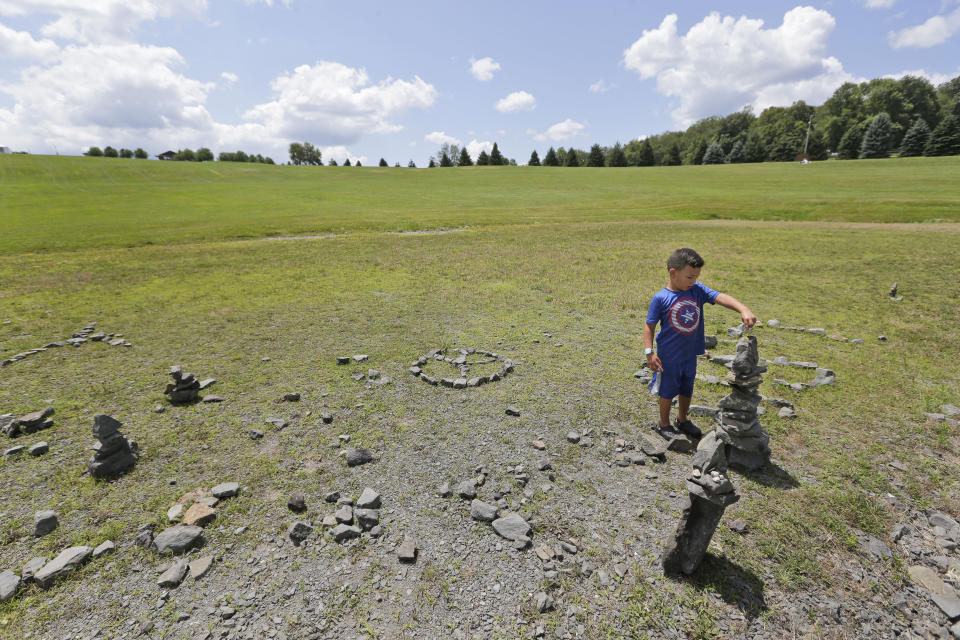 Caleb Hairston, 4, leaves flowers he picked on what used to be the stage of the 1969 Woodstock Music and Arts Fair, Wednesday, July 24, 2019, in Bethel, N.Y. Woodstock will be celebrated on its 50th anniversary, but it won't be your hippie uncle's trample-the-fences concert. While plans for a big Woodstock 50 festival collapsed after a run of calamities, the bucolic upstate New York site of the 1969 show is hosting a long weekend of events featuring separate shows by festival veterans like Carlos Santana and John Fogerty. (AP Photo/Seth Wenig)