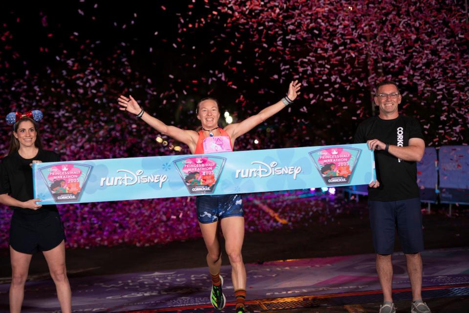  (Feb. 26, 2023) Neely Gracey throws her hands up in victory as she crosses the finish line as the overall race winner of the 13.1-mile Disney Princess Half Marathon presented by CORKCICLE in Lake Buena Vista, Fla. The Colorado resident is only the third woman in runDisney history to be the overall half marathon winner. (Elisa White, photographer)