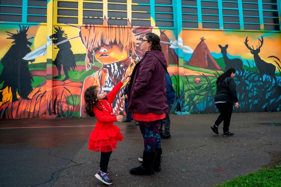 Iris Williams, 4, reaches for her mother Viola Williams, a tribal citizen of the Wilton Rancheria, during the unveiling of a mural on the outside of the gym at Miwok Middle School on Saturday that celebrates its name change from Sutter Middle School. Lezlie Sterling/lsterling@sacbee.com
