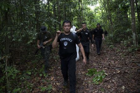 Members of a police forensic team carry a body bag with human remains dug from the grave near the abandoned human trafficking camp in the jungle close the Thailand border at Bukit Wang Burma in northern Malaysia May 27, 2015. REUTERS/Damir Sagolj