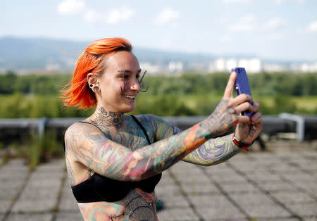 Kaitlin, 28, from the United States takes a selfie as she waits to be suspended by the professional body artist Dino Helvida in Zagreb, Croatia June 7, 2016. REUTERS/Antonio Bronic