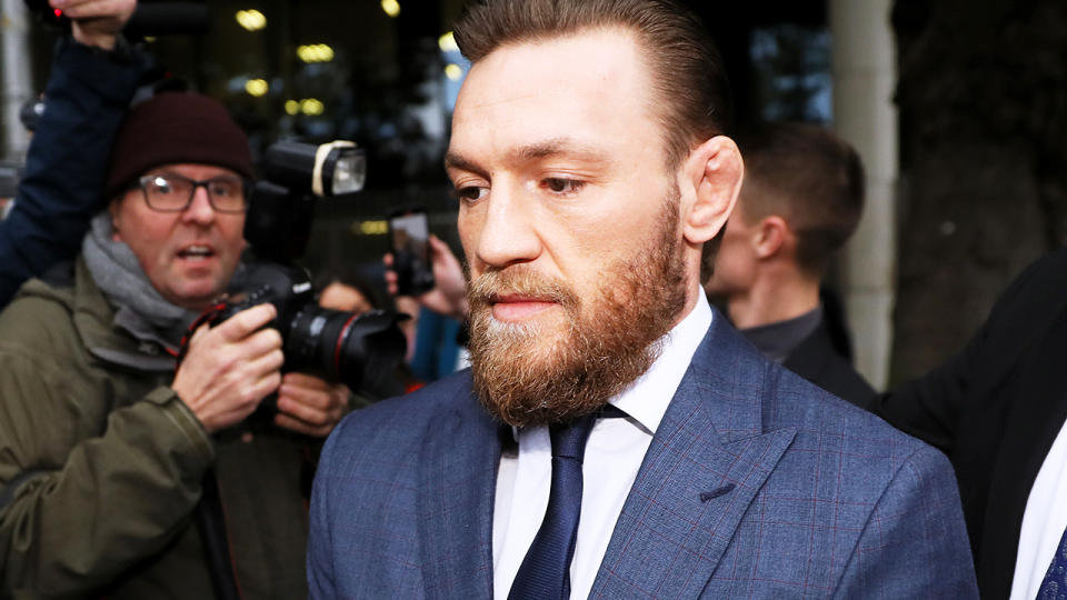 UFC fighter Conor McGregor in a suit walking away from media.
