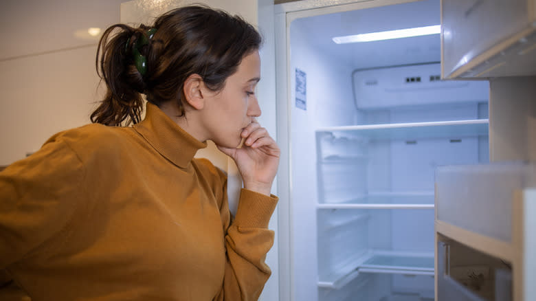 Person contemplating fridge interior