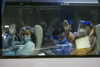 Chinese tourists from Shanghai, who arrived at Suvarnabhumi airport on special tourist visas, wave from a transit bus at Suvarnabhumi airport in Bangkok, Thailand, Tuesday, Oct. 20, 2020. Thailand on Tuesday took a modest step toward reviving its coronavirus-battered tourist industry by welcoming 39 visitors who flew in from Shanghai, the first such arrival since normal traveler arrivals were banned almost seven months ago. (AP Photo/Wason Wanichakorn)