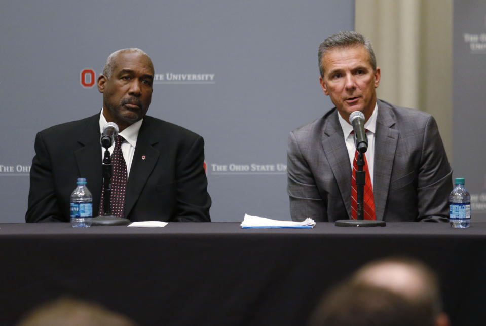 Ohio State football coach Urban Meyer, right, answers questions as athletic director Gene Smith listens during a news conference in Columbus, Ohio, Wednesday, Aug. 22, 2018. Ohio State suspended Meyer on Wednesday for three games for mishandling domestic violence accusations, punishing one of the sport's most prominent leaders for keeping an assistant on staff for several years after the coach's wife accused him of abuse. Athletic director Smith was suspended from Aug. 31 through Sept. 16. (AP Photo/Paul Vernon)
