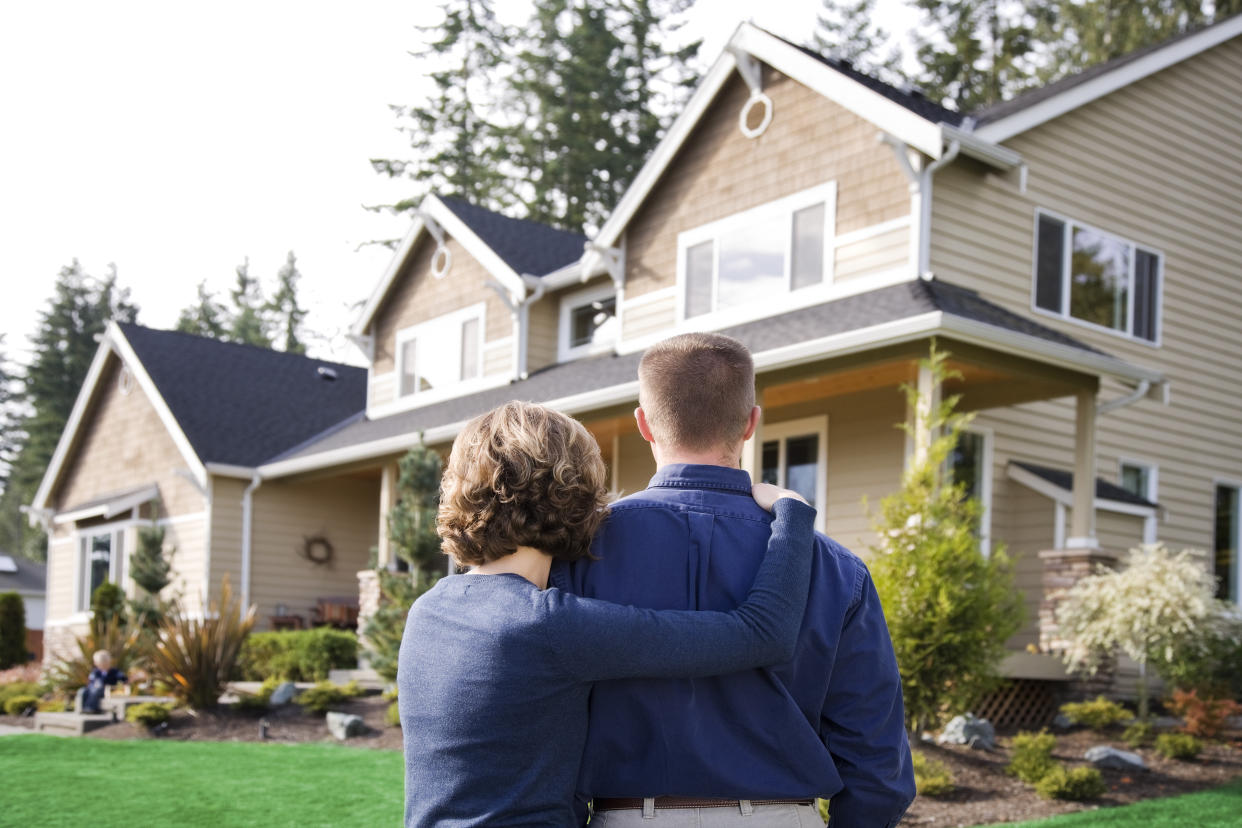 Loving couple House shopping with their son playing in the distance on the steps