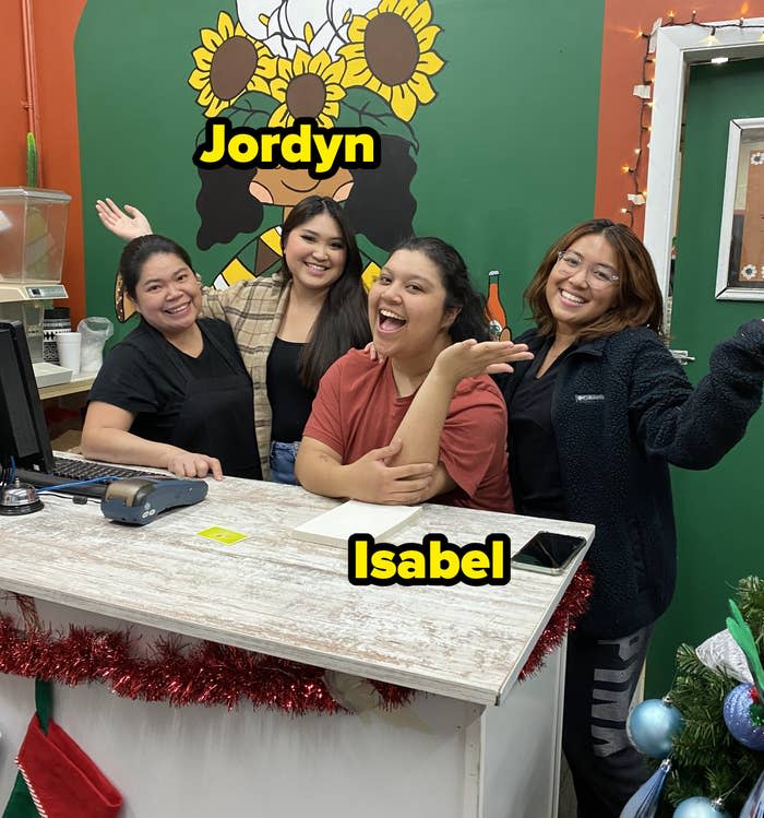 Jordyn and Isabel posing in front of painted wall behind cash register in restaurant with family