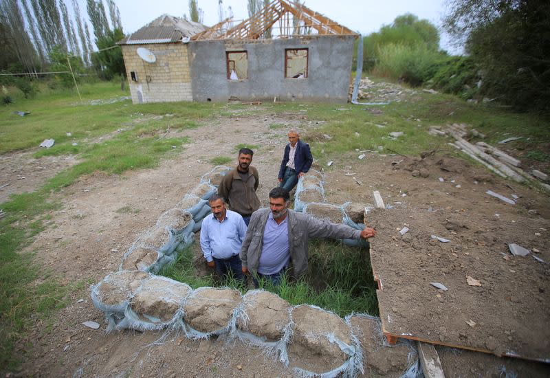 Local residents gather outside a dugout during the fighting over the breakaway region of Nagorno-Karabakh in the city of Terter