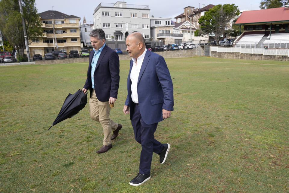 Australian Rugby's head coach Eddie Jones, right, and Mark McCartney, head of communications for Rugby Australia, stroll on the pitch at Coogee Oval before Jones speaks to media in Sydney, Tuesday, Oct. 17, 2023. Wallabies head coach, Jones, says he is "committed to Australia" amid numerous reports that he is planning to quit and take up the Japan coaching job for a second time. (AP Photo/Rick Rycroft)