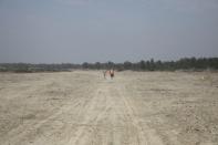 Construction workers walk along the Vashan Char, previously known as Thengar Char island, in the Bay of Bengal, Bangladesh February 14, 2018. Picture taken February 14, 2018. REUTERS/Stringer