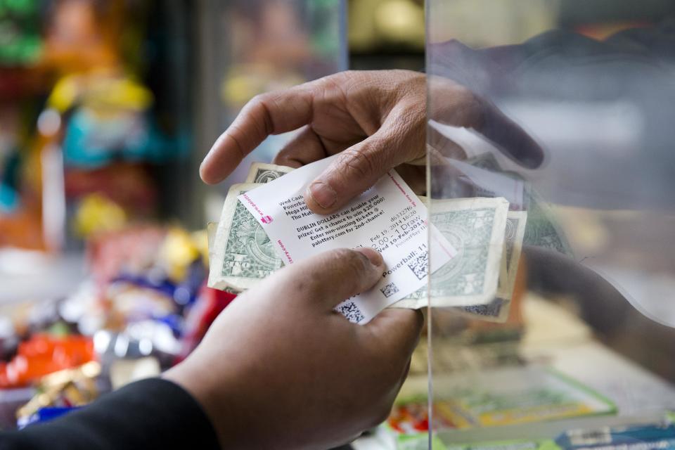 Atul Amin, right, sells Powerball tickets at his news stand Wednesday, Feb. 19, 2014, in Philadelphia. The estimated Powerball lottery jackpot is $400 million. (AP Photo/Matt Rourke)