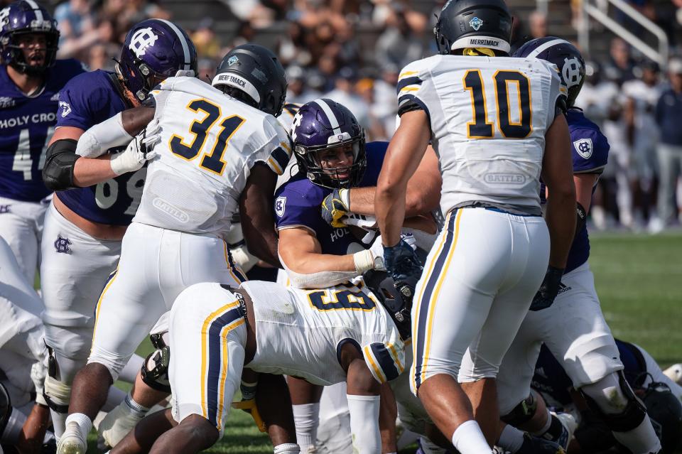 Holy Cross's Jordan Fuller, center, pushes thorugh a wall of Merrimack defenders for his third touchdown of the game Saturday at Fitton Field.