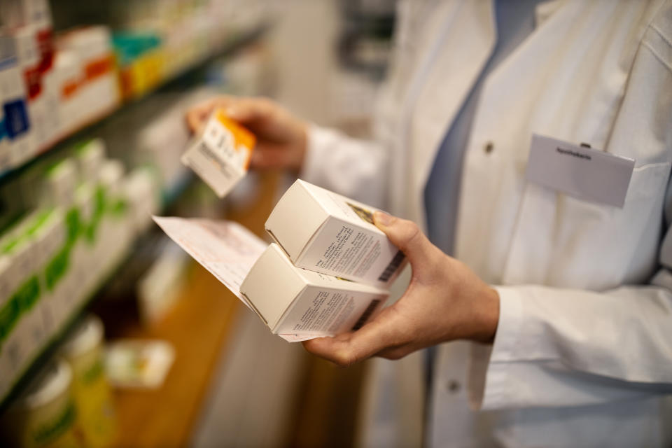 Close-up of female pharmacist's hand with prescription searching medicines in rack. Chemist is looking for medicine in storage rack.