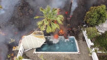 Hot lava reaches a swimming pool after an eruption of a volcano on the island of La Palma in the Canaries, Spain, Monday, Sept. 20, 2021. Giant rivers of lava are tumbling slowly but relentlessly toward the sea after a volcano erupted on a Spanish island off northwest Africa. The lava is destroying everything in its path but prompt evacuations helped avoid casualties after Sunday's eruption. (Europa Press via AP)