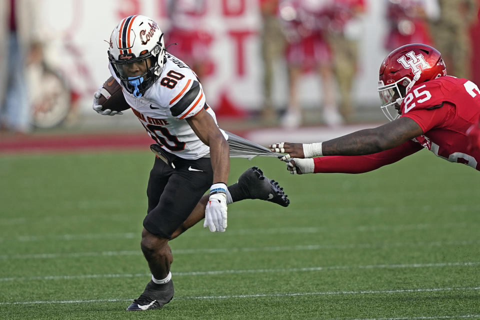 Houston linebacker Jamal Morris (25) grabs the shirt of Oklahoma State wide receiver Brennan Presley (80) during the first half of an NCAA college football game Saturday, Nov. 18, 2023, in Houston. (AP Photo/David J. Phillip)