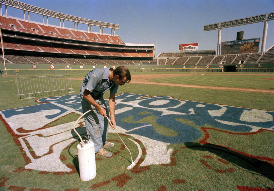 FILE - In this October 1984 file photo, a groundskeeper at Jack Murphy Stadium paints the logo for the 1984 World Series between San Diego Padres and Detroit Tigers in San Diego. The biggest piece of San Diego's sports history is slowly being knocked down and ground to bits. Now the stadium is coming to an unceremonious end, leaving generations of fans feeling melancholy because, due to the coronavirus pandemic, they didn't get to say a proper goodbye to the place where they tailgated with gusto in the massive parking lot before cheering on the Chargers, Padres and Aztecs, or watched myriad other events and concerts. (AP Photo,File)