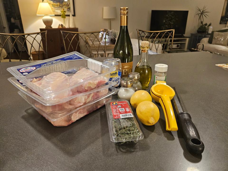 Packages of chicken breast, thyme, two lemons, juicer, olive oil on counter