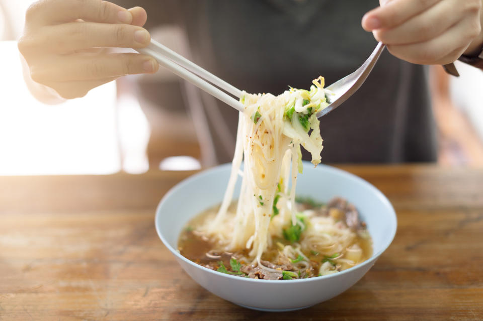 A person eating a bowl of noodle soup