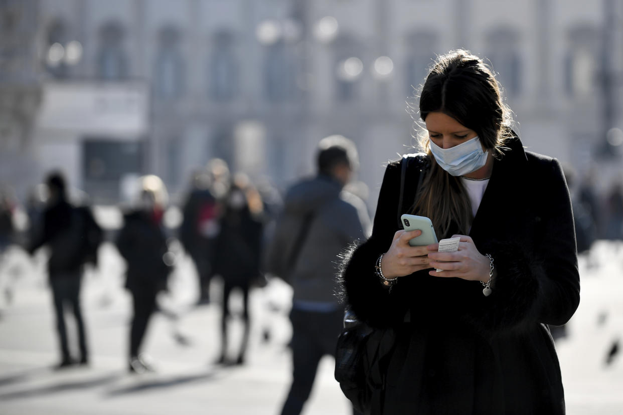 A woman wearing a sanitary mask looks at her phone in Milan, Italy, Monday, Feb. 24, 2020. At least 190 people in Italy’s north have tested positive for the COVID-19 virus and four people have died, including an 84-year-old man who died overnight in Bergamo, the Lombardy regional government reported. (Claudio Furlan/Lapresse via AP)