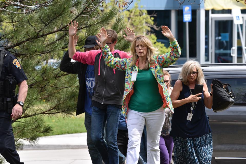 Students and teachers raise their arms as they exit the scene of a shooting in Highlands Ranch, Colorado, on May 7 , 2019..