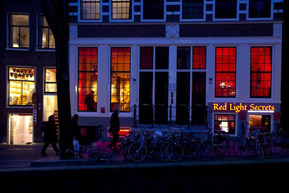 In this photo taken Tuesday, Feb. 4, 2014, the entrance of the 'Red Light Secrets' prostitution museum is seen, right, in Amsterdam. On any given evening, thousands of tourists stroll down the narrow streets of Amsterdam's famed Red Light District, gawking at ladies in lingerie who work behind windows, making a living selling sex for money. Now a small educational museum is opening in heart of the district that aims to show reality from the other side of the glass. Organizer Melcher de Wind says the Red Light Secrets museum is for those who want to learn more about how the area works without actually visiting a prostitute. (AP Photo/Evert Elzinga)