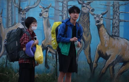 Foreign tourists carry their luggage as they wait for a passanger vehicle before leaving Srinagar