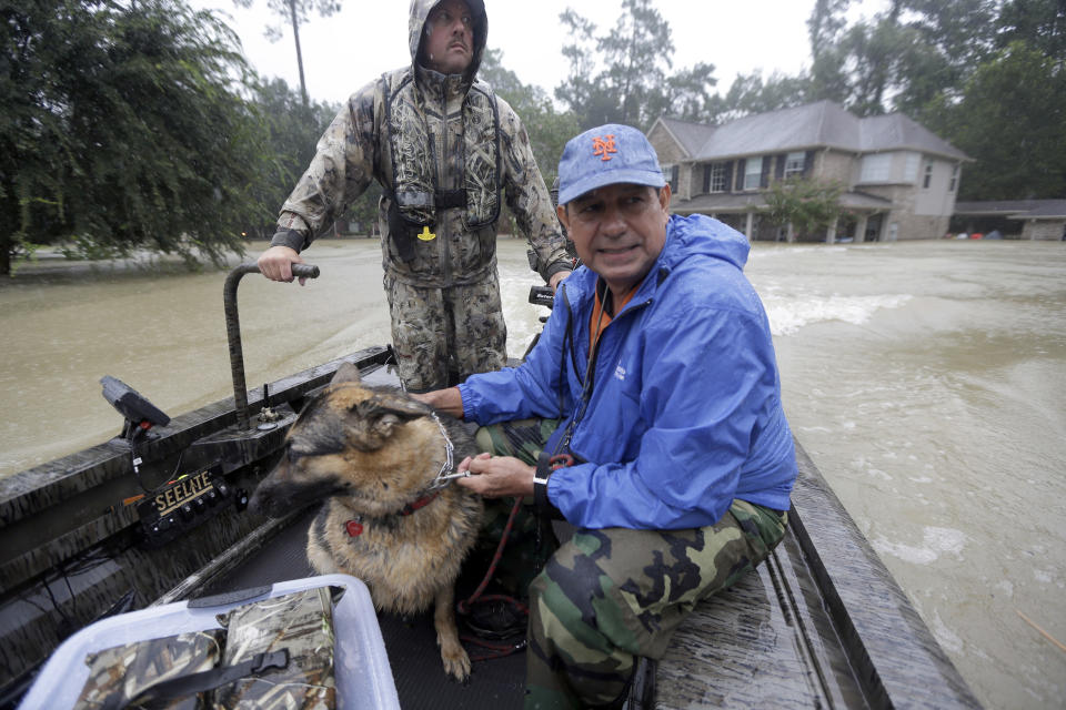 <p>Joe Garcia, right, and his dog Heidi ride in Murphy Fire Department’s Todd Herrington’s boat after being rescued from his flooded home as floodwaters from Tropical Storm Harvey rise, Aug. 28, 2017, in Spring, Texas. (Photo: David J. Phillip/AP) </p>