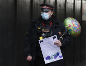 A policeman carries a well wisher's card and ballon outside St Bartholomew's Hospital where Britain's Prince Philip is being treated, in London, Wednesday, March 3, 2021. Prince Philip, the 99-year-old husband of Queen Elizabeth II, was transferred from King Edward VII's Hospital to St Bartholomew's Hospital to undergo testing and observation for a pre-existing heart condition as he continues treatment for an unspecified infection. (AP Photo/Alastair Grant)