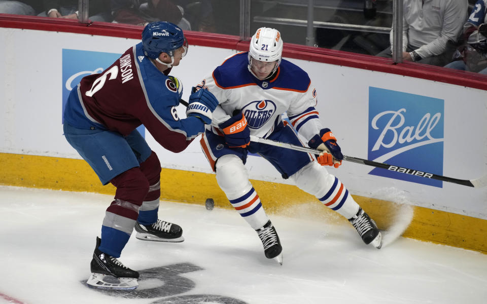 Colorado Avalanche defenseman Erik Johnson, left, fights for control of the puck against Edmonton Oilers center Klim Kostin during the first period of an NHL hockey game Tuesday, April 11, 2023, in Denver. (AP Photo/David Zalubowski