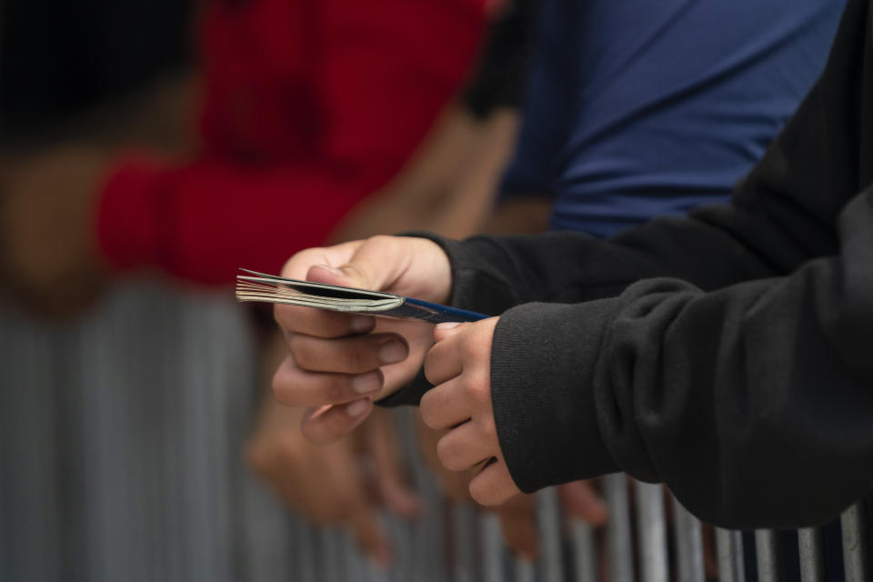 FILE - A migrant holds a passport as he waits with the rest of the group at the Gateway International Port of Entry under U.S. Customs and Border Protection custody before being sent back to Mexico under Title 42 in Brownsville, Texas, Friday, May 5, 2023. The Biden administration has stopped taking appointments via its mobile phone app from asylum seekers in a notoriously dangerous and corrupt Mexican border city amid signs migrants who used it were being targeted for extortion. (AP Photo/Veronica G. Cardenas, File)