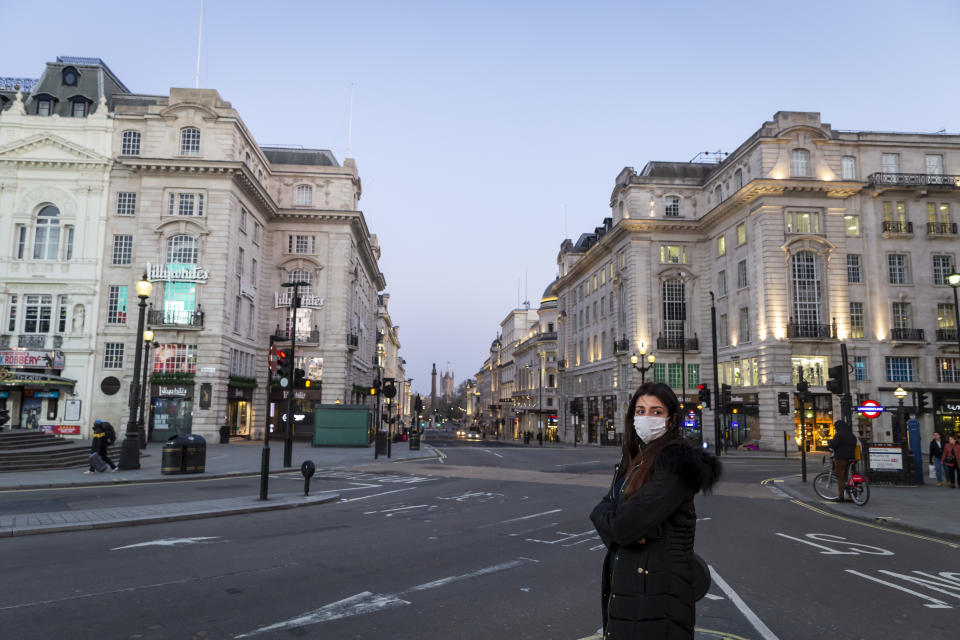 A woman wearing a face mask stands in an almost deserted Picadilly Circus in London on March 27th, 2020. The centre of London is extremely quiet with almost every business closed and very few people about because of the Government's lockdown measures due to the Coronavirus crisis. (Photo by Jonathan Perugia/In Pictures via Getty Images)