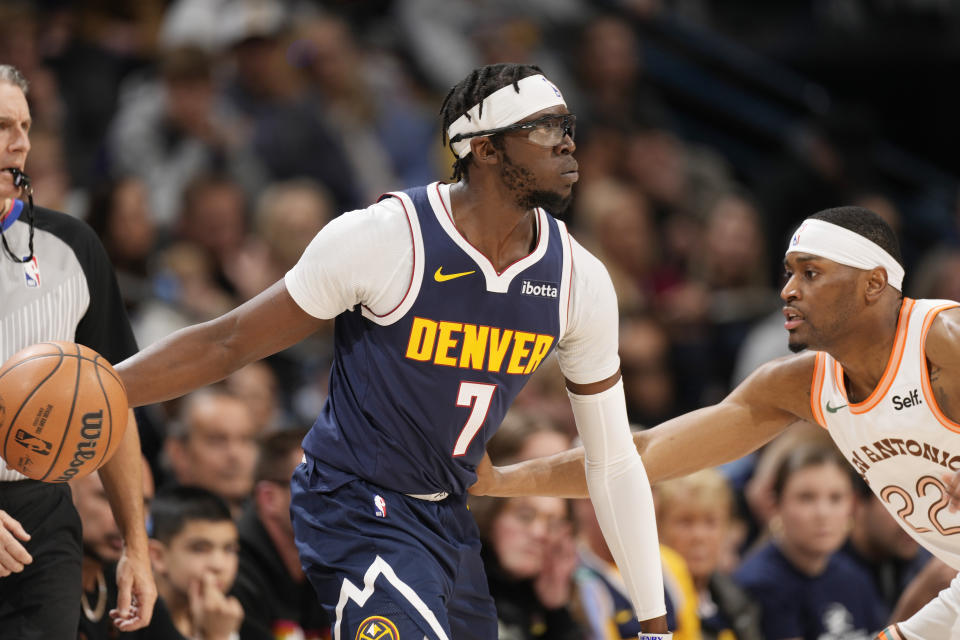 Denver Nuggets guard Reggie Jackson (7) looks to pass the ball as San Antonio Spurs guard Malaki Branham, right, defends in the first half of an NBA basketball game Sunday, Nov. 26, 2023, in Denver. (AP Photo/David Zalubowski)