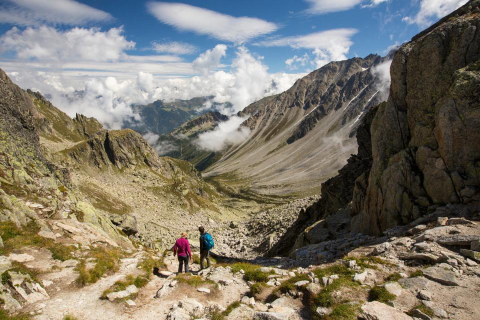 A couple on the Tour du Mont Blanc descend into the Val D' Arpette in the Swiss Alps.