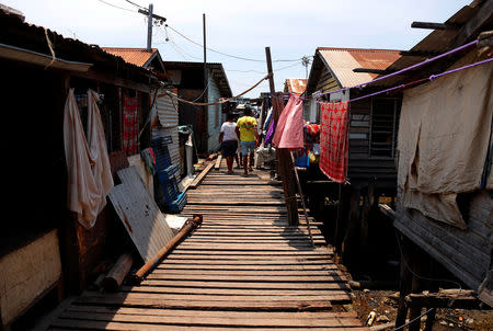 Residents walk to their houses on a wooden path surrounded by clothes hanging on lines between stilt houses at Hanuabada Village, located in Port Moresby Harbour, Papua New Guinea, November 19, 2018. REUTERS/David Gray