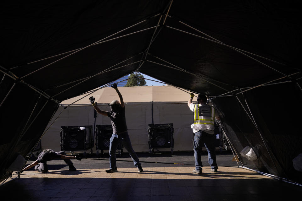 Volunteers help build a mobile field hospital at UCI Medical Center, Monday, Dec. 21, 2020, in Orange, Calif. California's overwhelmed hospitals are setting up makeshift extra beds for coronavirus patients, and a handful of facilities in hard-hit Los Angeles County are drawing up emergency plans in case they have to limit how many people receive life-saving care. (AP Photo/Jae C. Hong)