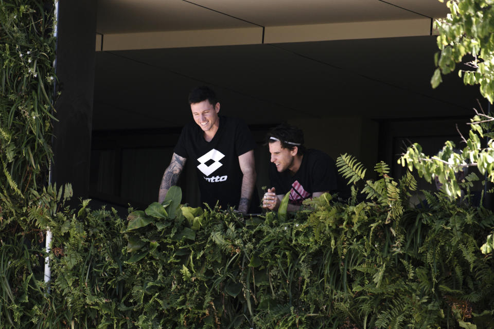 Austria's Dominic Thiem, right, with an unidentified man, stands on the balcony at his accommodation in Adelaide, Australia, Tuesday, Jan. 19, 2021. Australian Open tournament director Craig Tiley defended Serbia's Novak Djokovic for appealing to Australian Open organizers to ease restrictions so players could move to private residences with tennis courts. (Morgan Sette/AAP Image via AP)