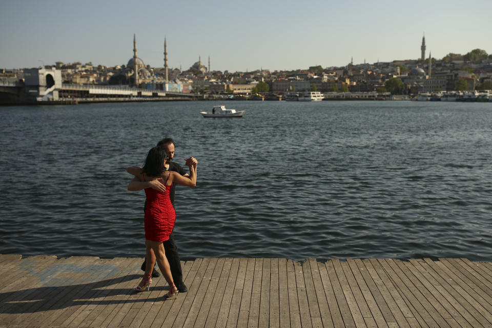 A couple dance by the Golden Horn leading to the Bosphorus Strait separating Europe and Asia, in Istanbul, Friday, May 14, 2021. Turkey is in the final days of a full coronavirus lockdown and the government has ordered people to stay home and businesses to close amid a huge surge in new daily infections. But millions of workers are exempt and so are foreign tourists. Turkey is courting international tourists during an economic downturn and needs the foreign currencies that tourism brings to help the economy as the Turkish lira continues to sink. (AP Photo/Emrah Gurel)