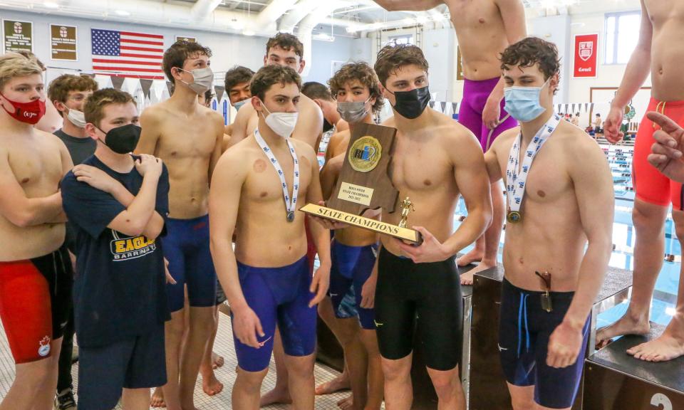 Barrington's Will McClelland holds the state championship trophy with teammates after Barrington's victory at the state meet on Saturday morning.