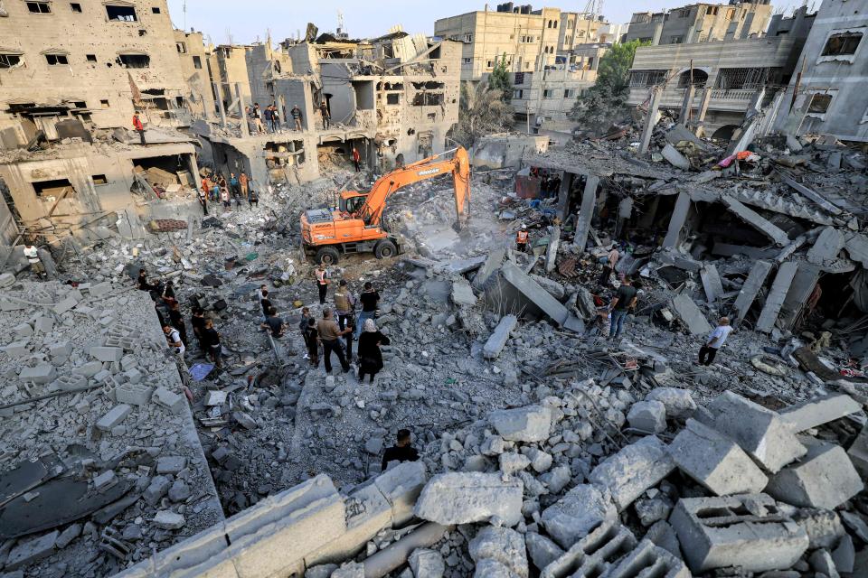 An excavator clears rubble as people search for survivors and the bodies of victims through buildings that were destroyed during Israeli bombardment of Khan Yunis, southern Gaza (AFP/Getty)