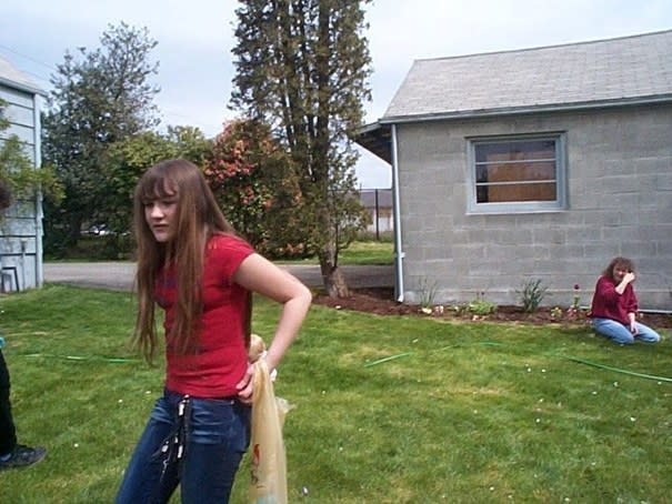 A young girl standing on grass and wearing jeans with keys hanging from the waist