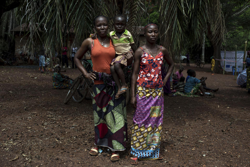 Monique Moukidje, 34, left, poses for a picture with her two children Marienne and Odalvia, in Mbangui-Ngoro, a Central African Republic village where she and hundreds of other displaced people who fled Bangassou found refuge, Monday Feb. 15, 2021. Moukidje fled her home when rebels attacked with heavy weapons. "I ran away because the bullets have no eyes" said Moukidje. (AP Photo/Adrienne Surprenant)